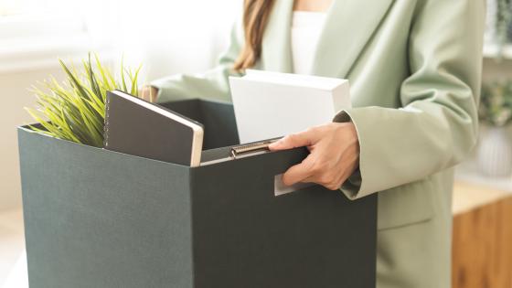 Woman walking out of office with box of belongings