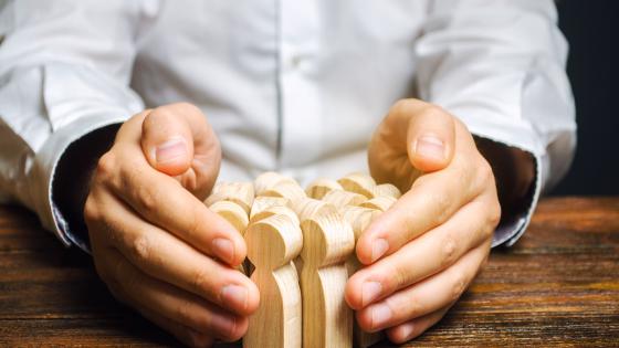 hands protecting wooden people