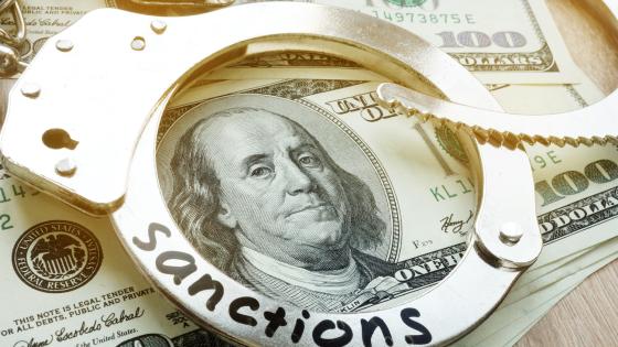 Word sanctions on a handcuffs and American dollar bills