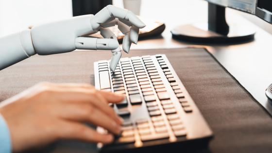 Person and robot both typing on keyboard