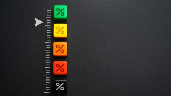 Percentage symbols on dice of different colours with a scale pointing to the green die